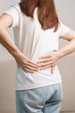 Evdeki koltukta otururken sırt ağrısı çeken bir kadın. Piriforis Sendromu, bel ağrısı ve omurga baskısı nedeniyle kas ağrısı olan yetişkin bir kadın. Ofis sendromu ve tıbbi konsept