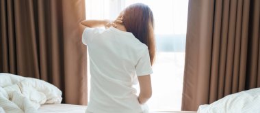 Evde yatakta otururken Neck ve Omuz ağrısı çeken bir kadın. Miyofasyal ağrı sendromu, fibromiyalji, romatizma, skapüler ağrı, boyun omurgası. Uyanış ve Sağlık kavramı