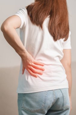 Evdeki koltukta otururken sırt ağrısı çeken bir kadın. Piriforis Sendromu, bel ağrısı ve omurga baskısı nedeniyle kas ağrısı olan yetişkin bir kadın. Ofis sendromu ve tıbbi konsept