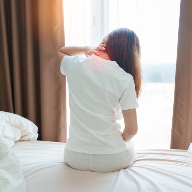 Evde yatakta otururken Neck ve Omuz ağrısı çeken bir kadın. Miyofasyal ağrı sendromu, fibromiyalji, romatizma, skapüler ağrı, boyun omurgası. Uyanış ve Sağlık kavramı