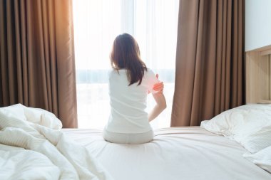 Evde yatakta yatarken kolu ağrıyan bir kadın, uyandıktan sonra kas hasarı ve ağrısı. Sağlık ve Tıp Konsepti