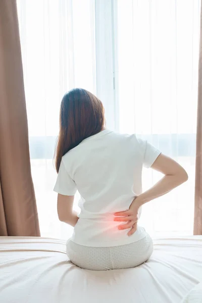 woman having back body ache during sitting on bed at home. adult female with muscle pain after Waking up due to Piriformis Syndrome, Low Back Pain and Spinal Compression. Health medical concept