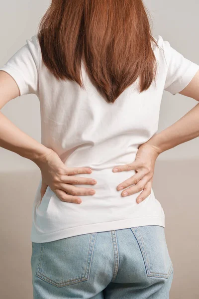 Evdeki koltukta otururken sırt ağrısı çeken bir kadın. Piriforis Sendromu, bel ağrısı ve omurga baskısı nedeniyle kas ağrısı olan yetişkin bir kadın. Ofis sendromu ve tıbbi konsept