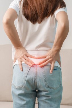 Evdeki koltukta otururken sırt ağrısı çeken bir kadın. Piriforis Sendromu, bel ağrısı ve omurga baskısı nedeniyle kas ağrısı olan yetişkin bir kadın. Ofis sendromu ve tıbbi konsept