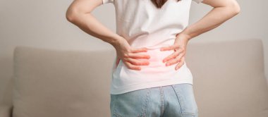 Evdeki koltukta otururken sırt ağrısı çeken bir kadın. Piriforis Sendromu, bel ağrısı ve omurga baskısı nedeniyle kas ağrısı olan yetişkin bir kadın. Ofis sendromu ve tıbbi konsept