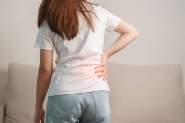 Evdeki koltukta otururken sırt ağrısı çeken bir kadın. Piriforis Sendromu, bel ağrısı ve omurga baskısı nedeniyle kas ağrısı olan yetişkin bir kadın. Ofis sendromu ve tıbbi konsept