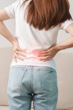Evdeki koltukta otururken sırt ağrısı çeken bir kadın. Piriforis Sendromu, bel ağrısı ve omurga baskısı nedeniyle kas ağrısı olan yetişkin bir kadın. Ofis sendromu ve tıbbi konsept