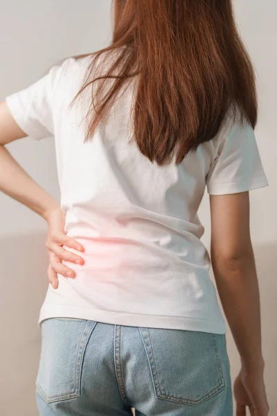 Evdeki koltukta otururken sırt ağrısı çeken bir kadın. Piriforis Sendromu, bel ağrısı ve omurga baskısı nedeniyle kas ağrısı olan yetişkin bir kadın. Ofis sendromu ve tıbbi konsept