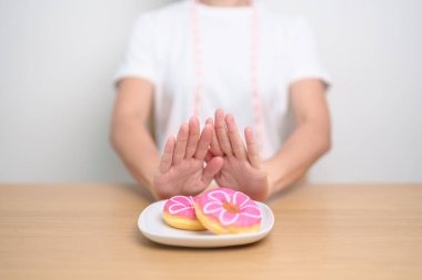 Kadın eli çöreği reddediyor, kadın sağlıksız abur cuburu reddediyor. Diyet kontrolü, kilo kaybı, obezite, yeme tarzı ve beslenme kavramları