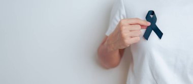 Melanoma ve cilt kanseri, aşı hasarı farkındalığı ayı ve huzur içinde yatma kavramları. Siyah kurdele tutan kadın