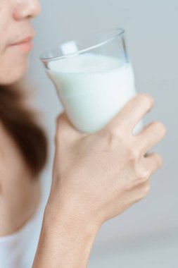 Süt içeceği ve günlük rutin konsepti. Genç bir kadın evde yüksek kalsiyum ve beslenme ile süt içiyor, kadın bardakta protein ile soya sütü tutuyor. Sağlıklı, sağlıklı ve mutlu bir yaşam tarzı.