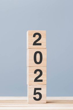 Masa arkasında 2025 metni olan tahta küp bloğu. Çözüm, plan, gözden geçirme, hedef, başlangıç ve yeni yıl tatili kavramları