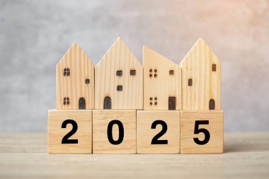 2025 mutlu yıllar, masada ev modeliyle. Bankacılık, gayrimenkul, yatırım, finans, tasarruf ve yeni yıl kararı kavramları