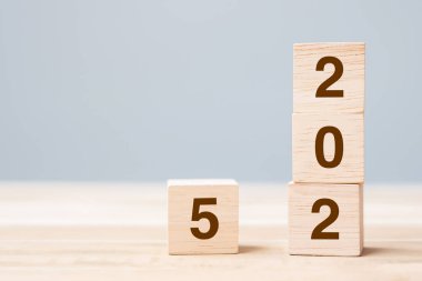 Masa arkasında 2025 metni olan tahta küp bloğu. Çözüm, plan, gözden geçirme, hedef, başlangıç ve yeni yıl tatili kavramları