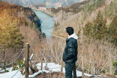 Tadami nehri ve köprüsü olan Japon tren manzaralı bir turist. Gezgin, Mishima Machi, Aizu, Fukushima Bölgesi, Japonya 'daki Tadami Demiryolu Hattı' na gidiyor. Simge ve simge noktası