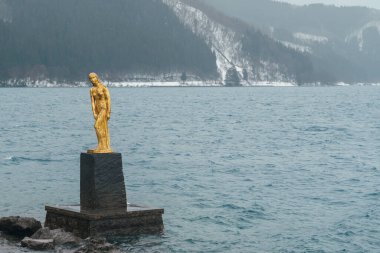 Efsanevi yerel kız Tatsuko ve kışın Tazawa Gölü 'nün ikonik altın heykeli. Semboku şehrinde, Akita Bölgesi, kuzey Japonya. Tohoku bölgesinde turistik ilgi merkezi