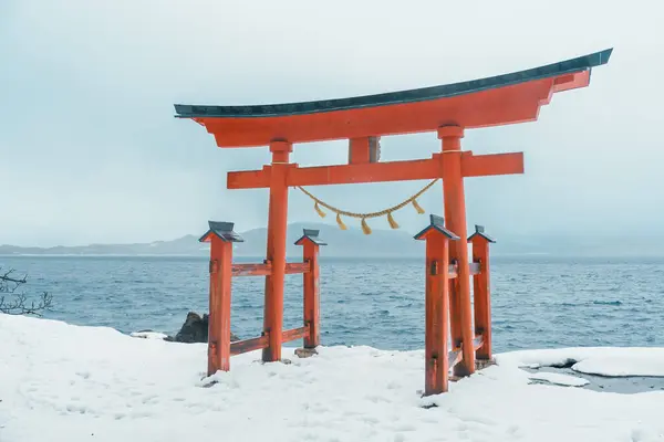 stock image Red Japanese Torii gate of Goza no Ishi Shrine at lake tazawa in winter, located in Semboku city, Akita Prefecture, northern Japan. Landmark and famous for tourists attractions in Tohoku region, Japan