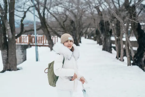 stock image Woman tourist sightseeing sakura trees with snow. Happy traveler travel near Hinokinai River riverbank in winter season locate in Kakunodate town, Semboku District, Akita Prefecture, Japan