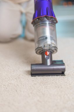 Halıyı kablosuz elektrik süpürgesiyle temizleyen kadın. Ev hanımı kablosuz süpürgeyi evi temizlemek için kullanıyor. Ev işleri, Temizlik, Temizlik, Temizlik, Toz, Temizlik ve günlük rutin