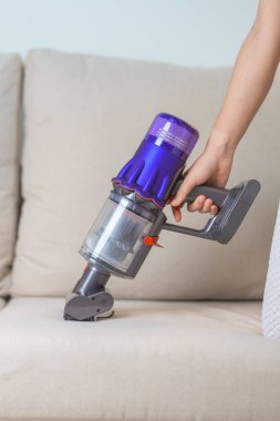 Kablosuz elektrik süpürgesiyle kanepeyi temizleyen kadın. Ev hanımı kablosuz süpürgeyi evi temizlemek için kullanıyor. Ev işleri, Temizlik, Temizlik, Temizlik, Toz, Temizlik ve günlük rutin