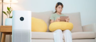 Kadının olduğu hava temizleyici. Rahat ol ve kanepede tablet kullan. Evde filtre ve temizlik tozu PM2.5 HEPA ve virüs için arıtma sistemi. Alerji, saf hava, sağlık, sağlık yaşam tarzı ve hava kirliliği.