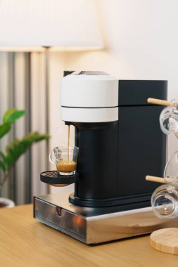 Kahve yaparken buharlı ve köpüklü Espresso bardağı. Kahve makinesinin yaptığı kahve, ahşap masa tezgahında. Kafe, günlük içecek içeceği Ev, Daire ve Ofis konsepti