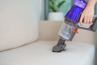 Kablosuz elektrik süpürgesiyle kanepeyi temizleyen kadın. Ev hanımı kablosuz süpürgeyi evi temizlemek için kullanıyor. Ev işleri, Temizlik, Temizlik, Temizlik, Toz, Temizlik ve günlük rutin