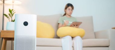 Kadının olduğu hava temizleyici. Rahat ol ve kanepede tablet kullan. Evde filtre ve temizlik tozu PM2.5 HEPA ve virüs için arıtma sistemi. Alerji, saf hava, sağlık, sağlık yaşam tarzı ve hava kirliliği.