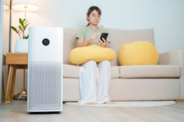 Kadının olduğu hava temizleyici. Rahat ol ve koltukta akıllı telefon kullan. Evde filtre ve temizlik tozu PM2.5 HEPA ve virüs için arıtma sistemi. Alerji, saf hava, sağlık, sağlık yaşam tarzı ve hava kirliliği.