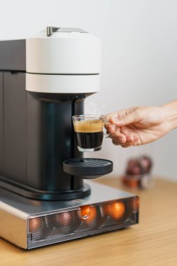 Kahve makinesinden Espresso Kahvesi ve ahşap masa çubuğunda kavrulmuş kahve çekirdeği. Ev, Apartman ve Ofis 'te günlük içecek konsepti