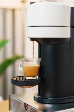 Kahve yaparken buharlı ve köpüklü Espresso bardağı. Kahve makinesinin yaptığı kahve, ahşap masa tezgahında. Kafe, günlük içecek içeceği Ev, Daire ve Ofis konsepti