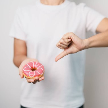 Kadın eli pembe donut, tatlı yemeyi bırakmak sağlıksız sağlıklı bir yemektir. Diyet kontrolü, kilo kaybı, obezite, yeme tarzı ve beslenme kavramları