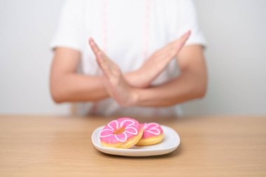 Kadın eli çöreği reddediyor, kadın sağlıksız abur cuburu reddediyor. Diyet kontrolü, kilo kaybı, obezite, yeme tarzı ve beslenme kavramları