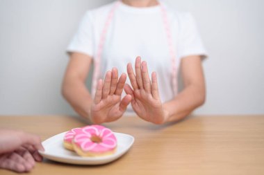 Kadın eli çöreği reddediyor, kadın sağlıksız abur cuburu reddediyor. Diyet kontrolü, kilo kaybı, obezite, yeme tarzı ve beslenme kavramları