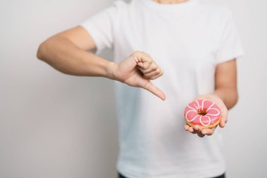 Kadın eli pembe donut, tatlı yemeyi bırakmak sağlıksız sağlıklı bir yemektir. Diyet kontrolü, kilo kaybı, obezite, yeme tarzı ve beslenme kavramları