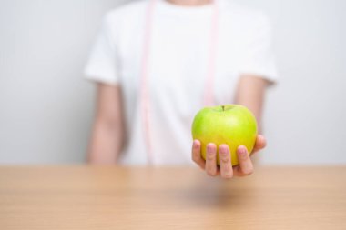 Yeşil Elma 'yı mezurayla tutan kadın, mutlu kadın meyvesini seçer sağlıklı yemektir. Diyet kontrolü, kilo kaybı, obezite, yeme tarzı ve beslenme kavramları