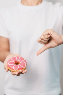 Kadın eli pembe donut, tatlı yemeyi bırakmak sağlıksız sağlıklı bir yemektir. Diyet kontrolü, kilo kaybı, obezite, yeme tarzı ve beslenme kavramları