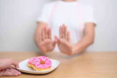 Kadın eli çöreği reddediyor, kadın sağlıksız abur cuburu reddediyor. Diyet kontrolü, kilo kaybı, obezite, yeme tarzı ve beslenme kavramları