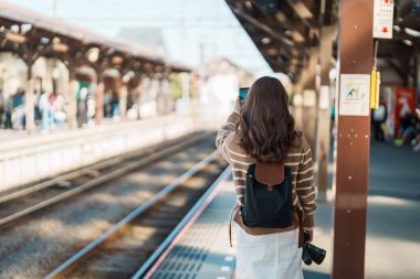 Kamakura, Kanagawa, Japonya 'da tren bekleyen ve ziyaret eden kadın turist. Gezginler Kamakura tren istasyonunu gezerken mutlu olsun. Tokyo yakınlarındaki turistler için önemli ve popüler bir yer. Seyahat ve Tatil
