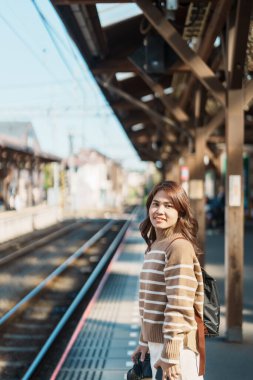 Woman tourist waiting train and Visiting in Kamakura, Kanagawa, Japan. happy Traveler sightseeing Kamakura train station. Landmark and popular for tourists attraction near Tokyo. Travel and Vacation clipart