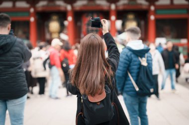 Sensoji Tapınağı 'nı ziyaret eden turist bir kadın veya Asakusa Kannon Tapınağı, Tokyo, Asakusa' da bulunan bir Budist tapınağıdır. Kırmızı fenerde Japonca cümle Şimşek kapısı anlamına gelir.