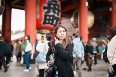 Sensoji Tapınağı 'nı ziyaret eden turist bir kadın veya Asakusa Kannon Tapınağı, Tokyo, Asakusa' da bulunan bir Budist tapınağıdır. Kırmızı fenerde Japonca cümle Şimşek kapısı anlamına gelir.