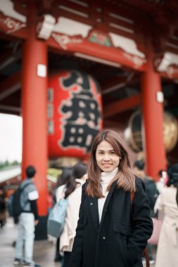 Sensoji Tapınağı 'nı ziyaret eden turist bir kadın veya Asakusa Kannon Tapınağı, Tokyo, Asakusa' da bulunan bir Budist tapınağıdır. Kırmızı fenerde Japonca cümle Şimşek kapısı anlamına gelir.