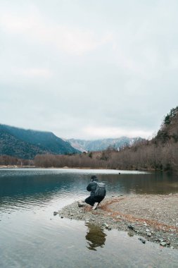 man  tourist travel Kamikochi National Park, happy Traveler sightseeing Taisho pond with mountain, Nagano Prefecture, Japan. Landmark for tourists attraction. Japan Travel, Destination and Vacation clipart