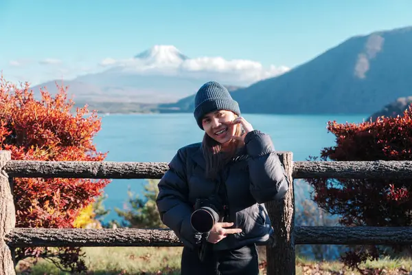 stock image Woman tourist with Fuji Mountain at Lake Motosu in Autumn season, happy Traveler travel Mount Fuji, Yamanashi, Japan. Landmark for tourists attraction. Japan Travel, Destination and Vacation