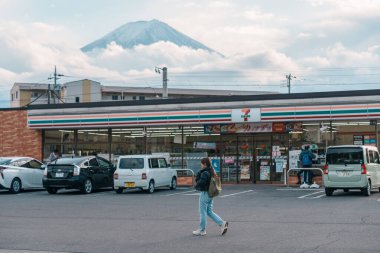 Turistler Kawaguchiko istasyonunun arkasında Fuji Dağı olan Seven Eleven mağazasını geziyorlar. Japonya 'da turistler için önemli ve popüler bir yer. Yamanashi, Japonya, 15 Kasım 2023