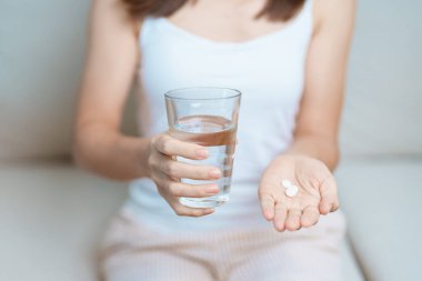 Kadının elinde ağrı kesici hap ve su bardağı vardı. Baş ağrısı, mide ağrısı, gıda zehirlenmesi, endometriyozis, histerektomi ve regl ağrıları için.