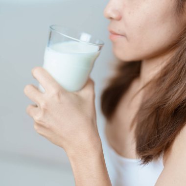 Süt içeceği ve günlük rutin konsepti. Genç bir kadın evde yüksek kalsiyum ve beslenme ile süt içiyor, kadın bardakta protein ile soya sütü tutuyor. Sağlıklı, sağlıklı ve mutlu bir yaşam tarzı.