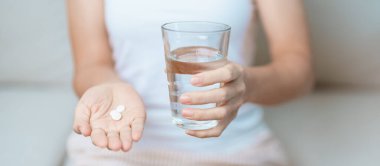 Kadının elinde ağrı kesici hap ve su bardağı vardı. Baş ağrısı, mide ağrısı, gıda zehirlenmesi, endometriyozis, histerektomi ve regl ağrıları için.
