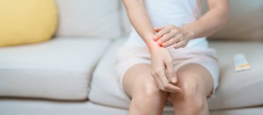 Eklem iltihabı ve kas ağrısı giderici krem konsepti. Evde bilek ağrısı çeken bir kadın, De Quervain 's tenosilovitis, ergonomik, Carpal Tunnel Sendromu veya Office Sendromu ve Parkinson yüzünden kas ağrısı çeken bir kadın.